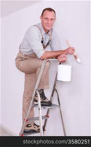 Man posing with paint brush whilst up ladder