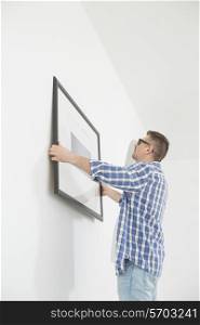 Man positioning picture frame on wall