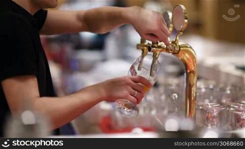 Man pouring draft beer into the glass from the tap