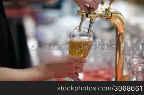 Man pouring full glass of draft beer, then turning off the tap and leaving