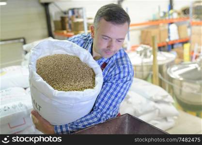 man pouring grains in a machine