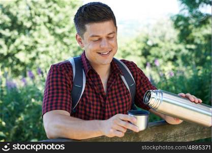 Man Pouring Hot Drink From Flask On Walk