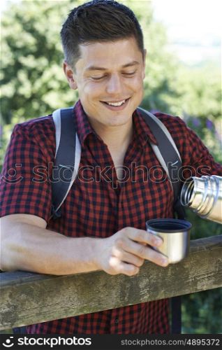 Man Pouring Hot Drink From Flask On Walk