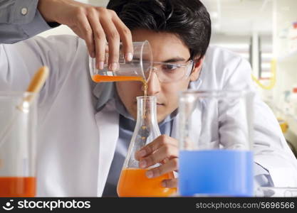 Man pouring liquid into a flask