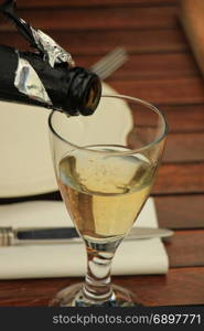 Man pouring white wine at a dinner table