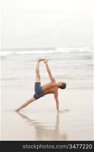 Man Practicing Yoga On The Beach