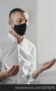 man praying alone home while wearing medical mask