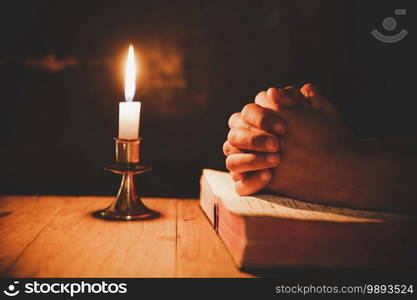 man praying on the Bible in the light candles selective focus