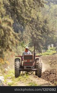 Man preparing the land for harvest with the tractor on the farm