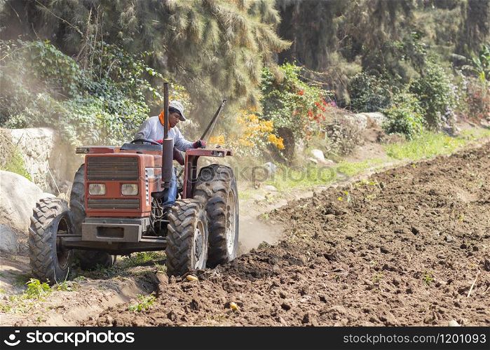 Man preparing the land for harvest with the tractor on the farm