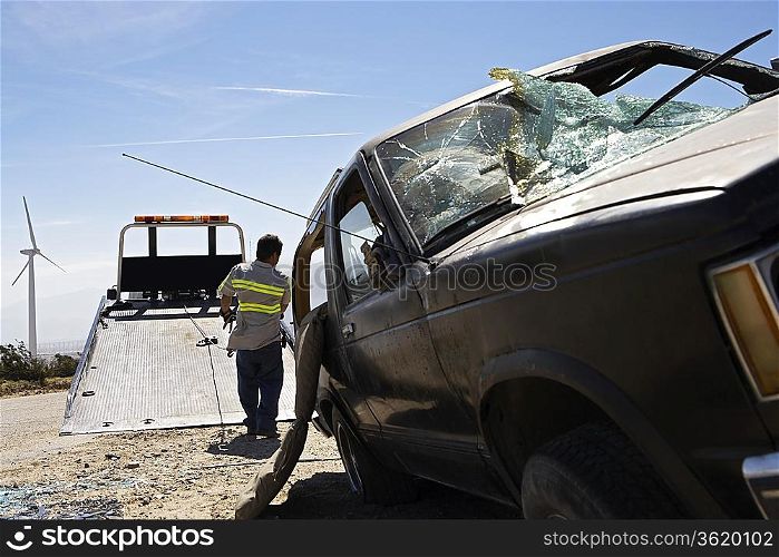 Man preparing to lift crashed car onto tow truck