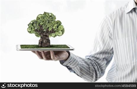 Man presenting green concept on tablet. Hand of businessman showing tablet with green gears tree on screen