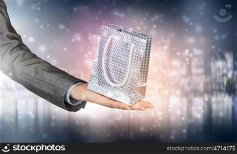 Man presenting his gift. Hand of elegant man holding gift bag in palm
