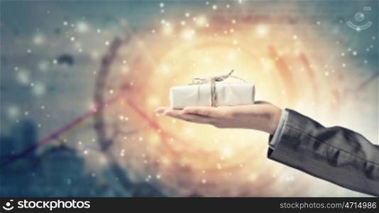 Man presenting his gift. Hand of elegant man holding gift box in palm