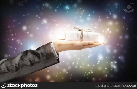 Man presenting his gift. Hand of elegant man holding gift box in palm