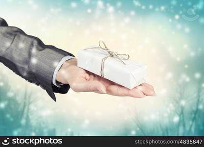 Man presenting his gift. Hand of elegant man holding gift box in palm