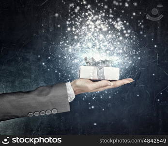 Man presenting his gift. Hand of elegant man holding gift box in palm