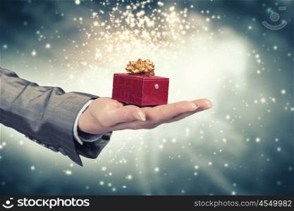 Man presenting his gift. Hand of elegant man holding red gift box in palm