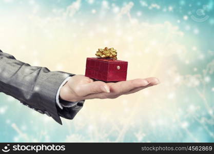 Man presenting his gift. Hand of elegant man holding red gift box in palm