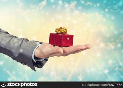 Man presenting his gift. Hand of elegant man holding red gift box in palm