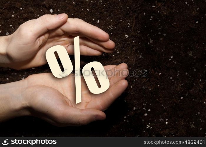 Man presenting his idea. Male hands on soil background showing in palms percent sign