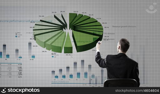 Man presenting report. Rear view of businessman drawing with marker infographs on wall