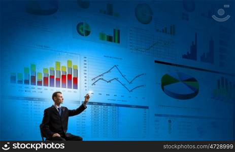 Man presenting report. Rear view of businessman drawing with marker infographs on wall