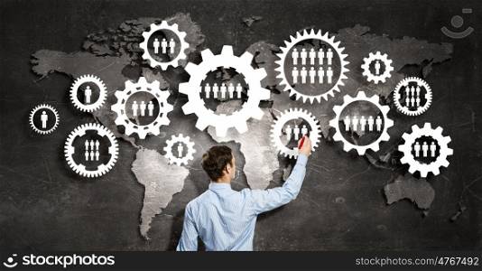 Man presenting teamwork concept. Back view of businessman standing with back and drawing gears mechanism