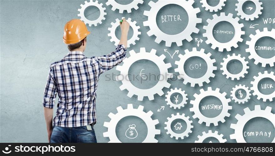 Man presenting teamwork concept. Back view of construction man standing with back and drawing gears mechanism