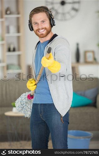 man pretending to play the guitar with a mop