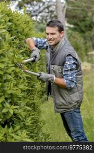 Man pruning hedge with shears