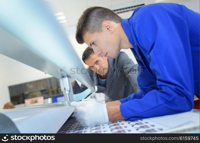 Man pulling paper through printing machine