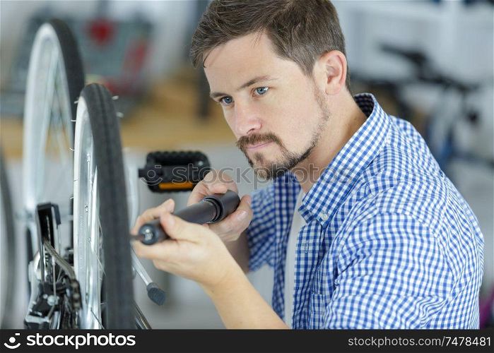 man pumping up a bike tire using small pump