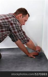 Man pushing lino flooring to fit into a corner