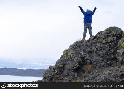 Man put his hands up on top of mountain, Lake Bikal in Russia