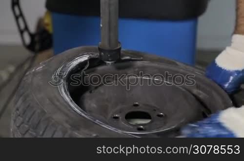 Man put on tire on car wheel by special tool,