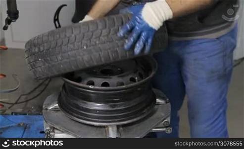 Man put on tire on car wheel by special tool