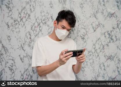 Man puts on a face mask using smartphone isolated on White background,pandemic and social distancing concept.Covid-19