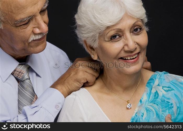 Man putting a necklace around her neck