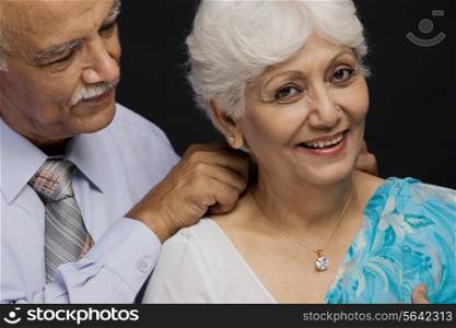 Man putting a necklace around her neck
