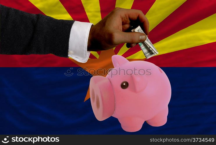 Man putting dollar into piggy rich bank flag of us state of arizona in foreign currency because of inflation