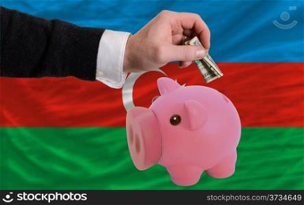 Man putting dollar into piggy rich bank national flag of azerbaijan in foreign currency because of inflation