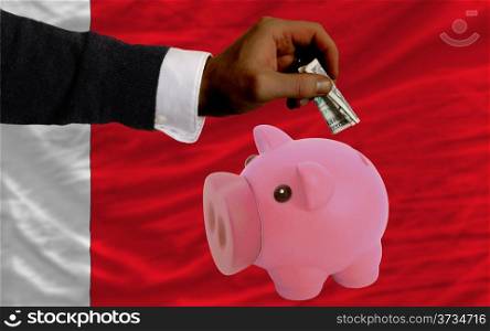 Man putting dollar into piggy rich bank national flag of bahrain in foreign currency because of inflation