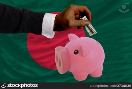 Man putting dollar into piggy rich bank national flag of bangladesh in foreign currency because of inflation
