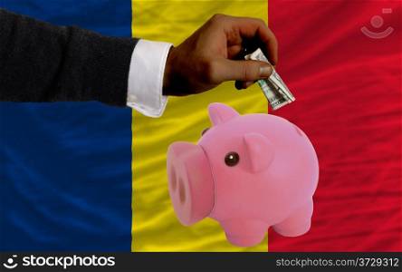Man putting dollar into piggy rich bank national flag of chad in foreign currency because of inflation