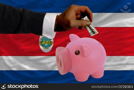 Man putting dollar into piggy rich bank national flag of columbia in foreign currency because of inflation