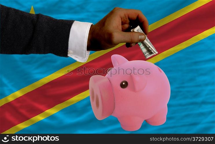 Man putting dollar into piggy rich bank national flag of congo in foreign currency because of inflation