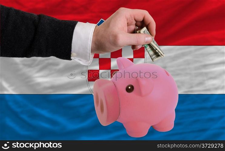 Man putting dollar into piggy rich bank national flag of croatia in foreign currency because of inflation