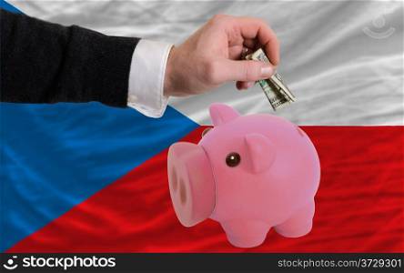 Man putting dollar into piggy rich bank national flag of czech in foreign currency because of inflation