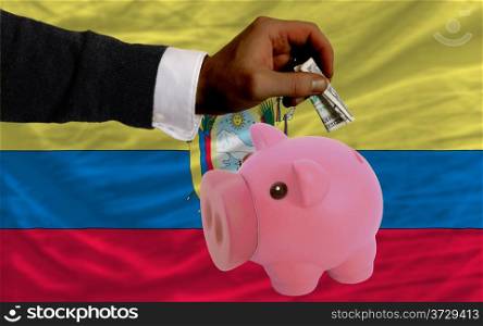 Man putting dollar into piggy rich bank national flag of ecuador in foreign currency because of inflation